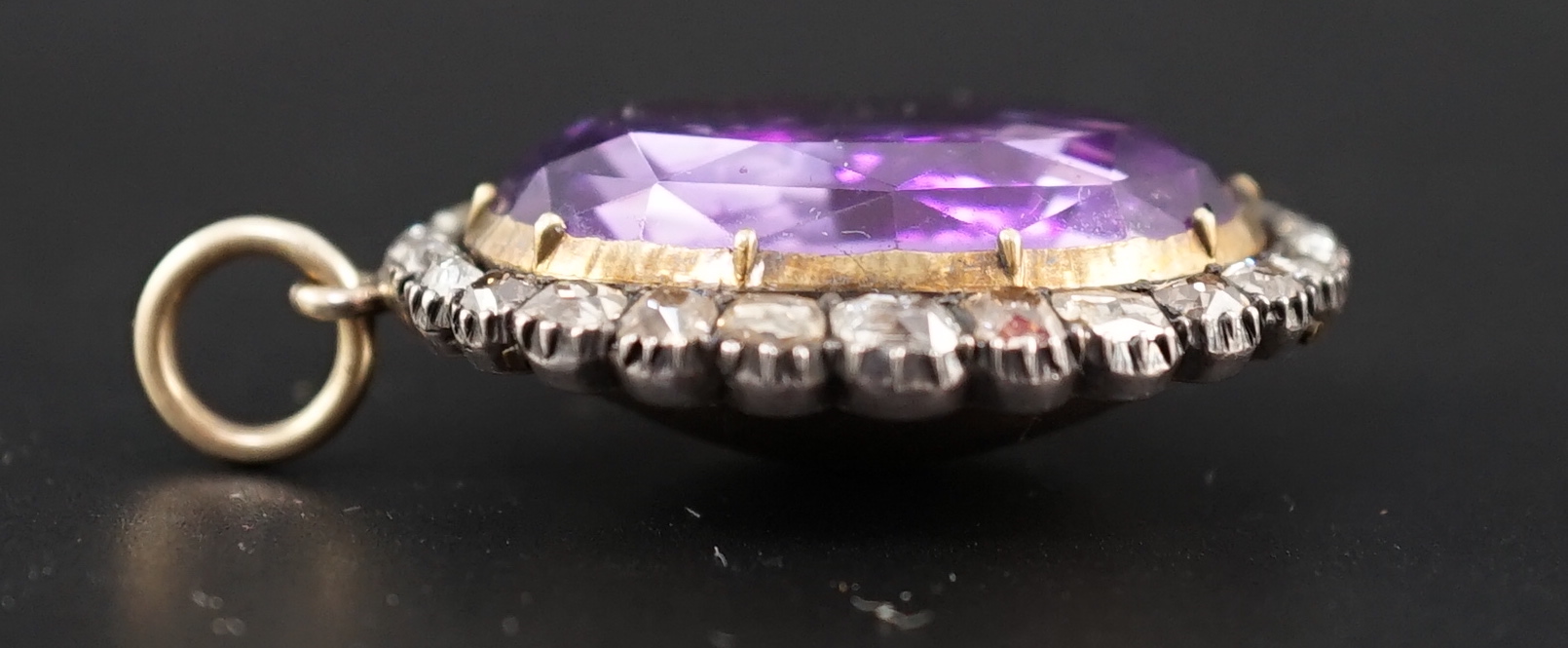 An early 19th century, gold and oval cut foil backed amethyst set pendant, with old cut diamond set border and closed back setting